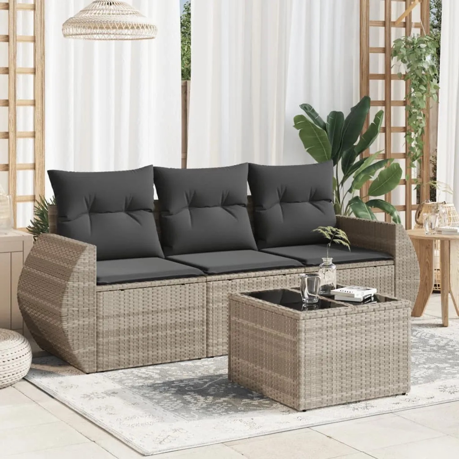 Hellgraue 4-tlg. Garten-Sofagarnitur aus Rattan mit dunklen Kissen und Tisch.