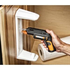 Worx WX255.4 Akku-Schrauber in Schwarz/Orange, wird einhändig zum Befestigen einer weißen Halterung an einem Holzschrank genutzt.