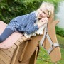 Mädchen auf roba Spielpferd mit rosa Decke und grauem Halfter im Garten. roba Accessoires Set für Spiel & Spaß.