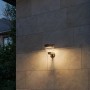 Schwarze Philips Solar-Außenwandleuchte Kyna mit warmweißem Licht an einer Hauswand.