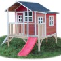 Rotes EXIT Loft 350 Holzspielhaus mit Rutsche und Leiter im Garten.