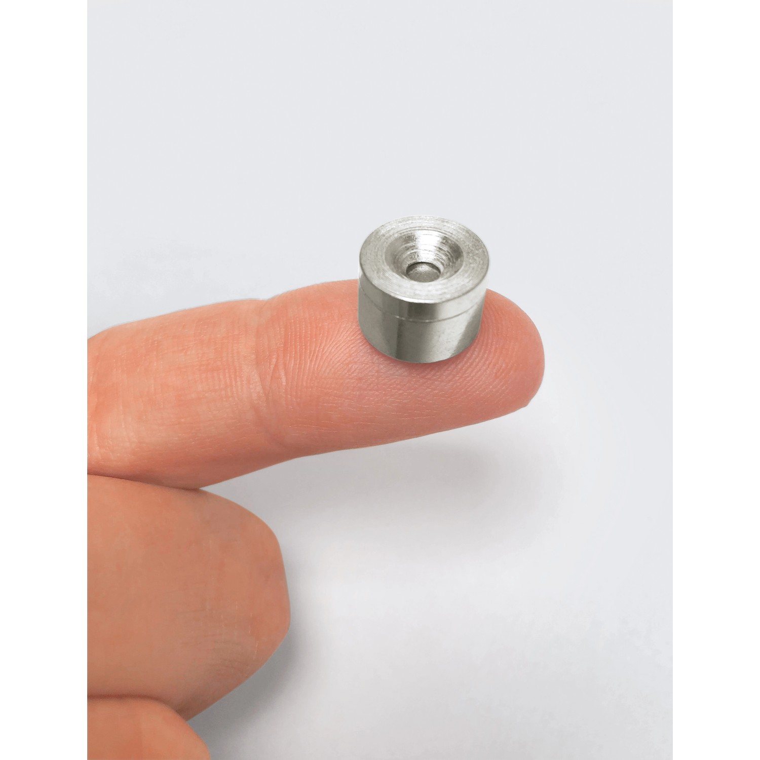 Fix-o-moll Magnetschnäpper Neodym, silberfarben, auf einem Finger liegend. Zum Einbohren für Möbel.