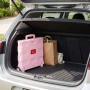 Rosafarbener, klappbarer Einkaufstrolley aus Kunststoff mit Rollen im Kofferraum eines Autos, bereit für den Transport.