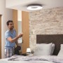 Silberne Philips Hue Deckenleuchte White Ambiance Still mit Dimmer in einem Schlafzimmer.