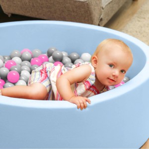 Baby im Bällebad mit LittleTom Bällebadbällen in Pink, Grau, Weiß und Transparent.