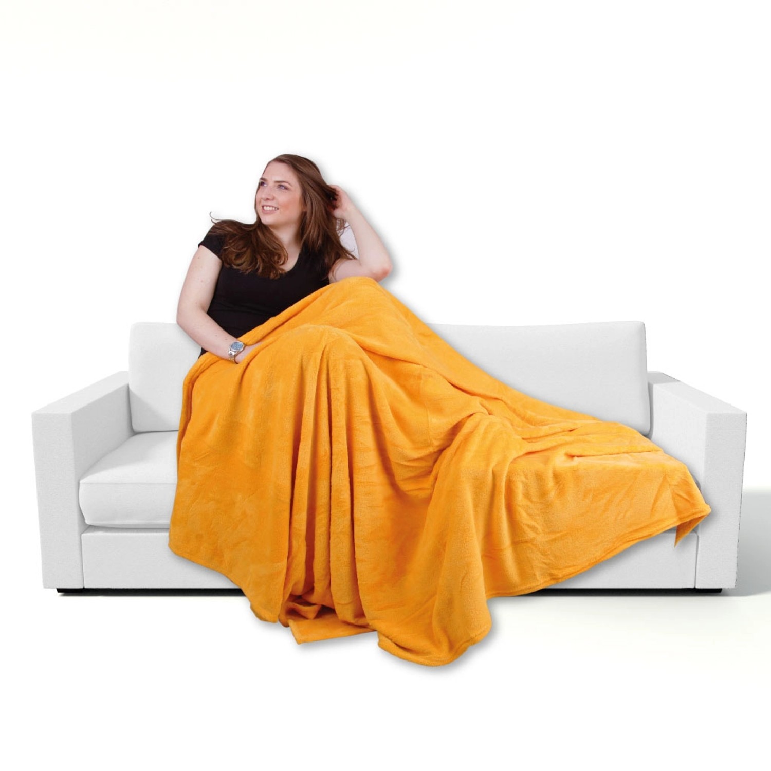 Frau sitzt auf Sofa, zugedeckt mit orange-apricotfarbener Mikrofaser Decke (130x170 cm).