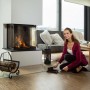 Frau reinigt Boden vor Kamin mit schwarzer Relaxdays Kehrgarnitur aus Stahl und Handfeger. Praktisches Reinigungsset für Haushalt.