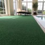 Foto von Primaflor Kunstrasen Summer B1, 2x1m, im Innenraum neben einem Pool. Grüner, kurzfloriger Rasenteppich.