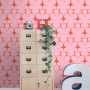 Rosa Vliestapete mit roten Retro-Ornamenten an einer Wand, die einen stilvollen Wohnraum dekoriert.