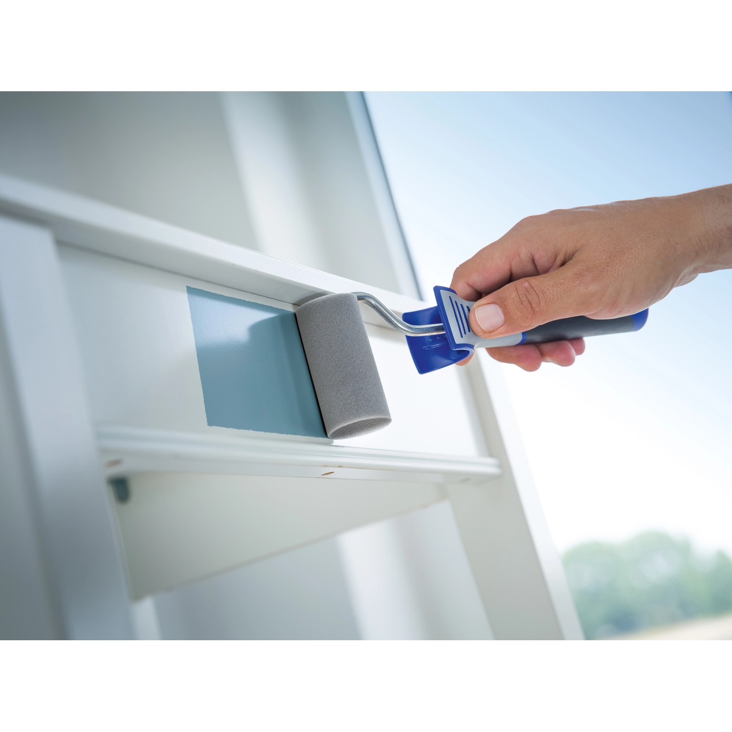 Hand streicht mit LUX Schaumwalze, 7 cm, konkav, eine weiße Fensterbank blau. Farbwalzen Set, 2 Stück.