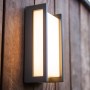 Moderne Lutec LED-Außenwandleuchte Qubo mit warmweißem Licht an Holzwand.