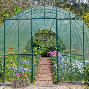 Kobolo Blumenbank LALE Rattan Pflanzkorb in Grau vor einem Gewächshaus mit Blumen.