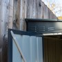 Offene Tür des anthrazitfarbenen Globel Metall-Anlehngerätehauses. Gerätehaus zur Wandmontage.
