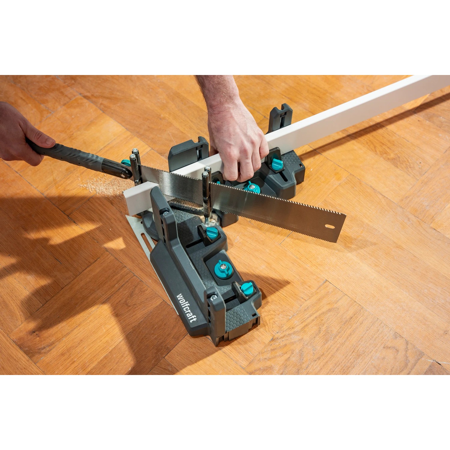 Wolfcraft Japansäge in Aktion mit Schmiege und Gehrungsschneidlade beim Sägen eines Werkstücks.