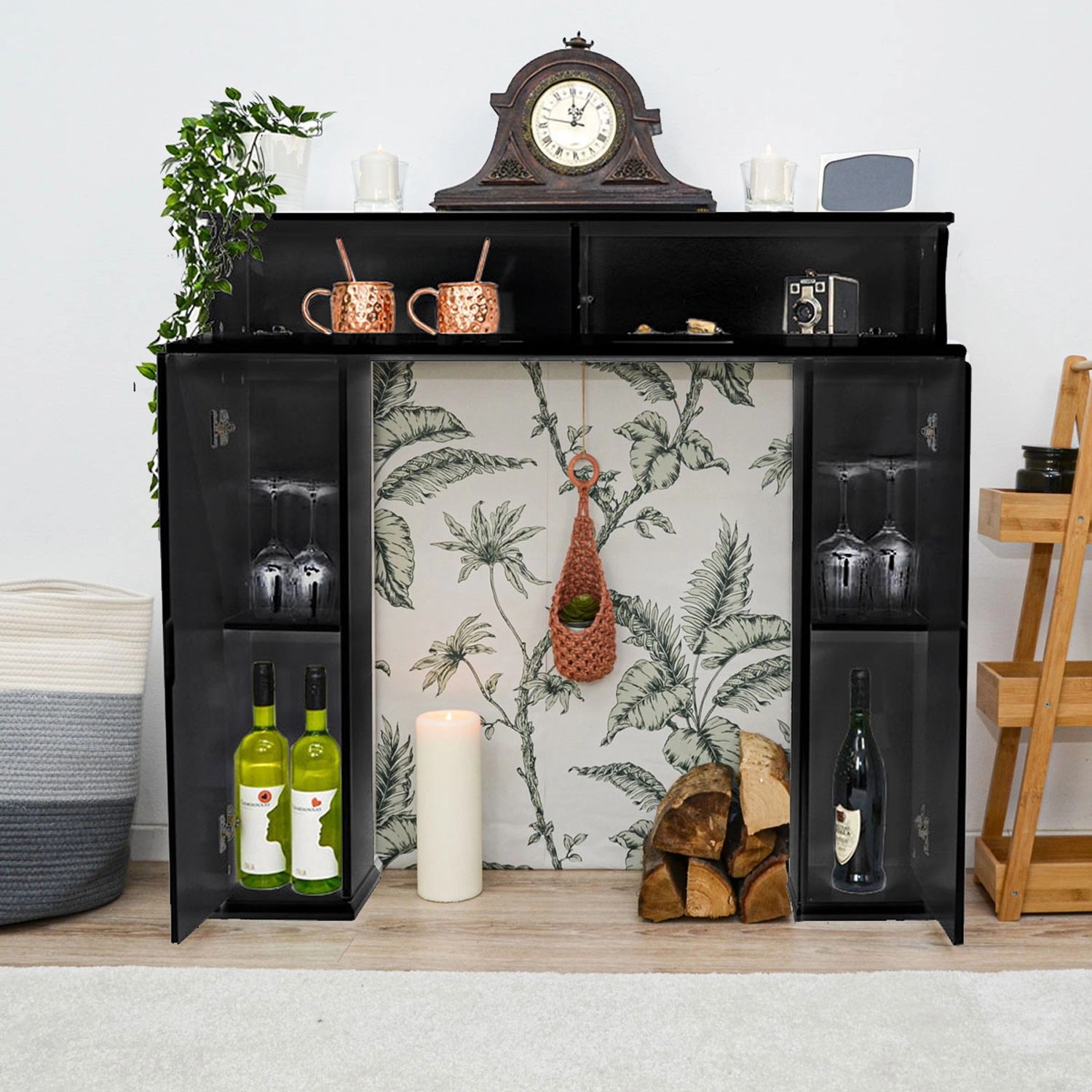 Schwarze DuneDesign Kaminkonsole mit Stauraum, dekoriert mit Uhr, Gläsern und Flaschen.
