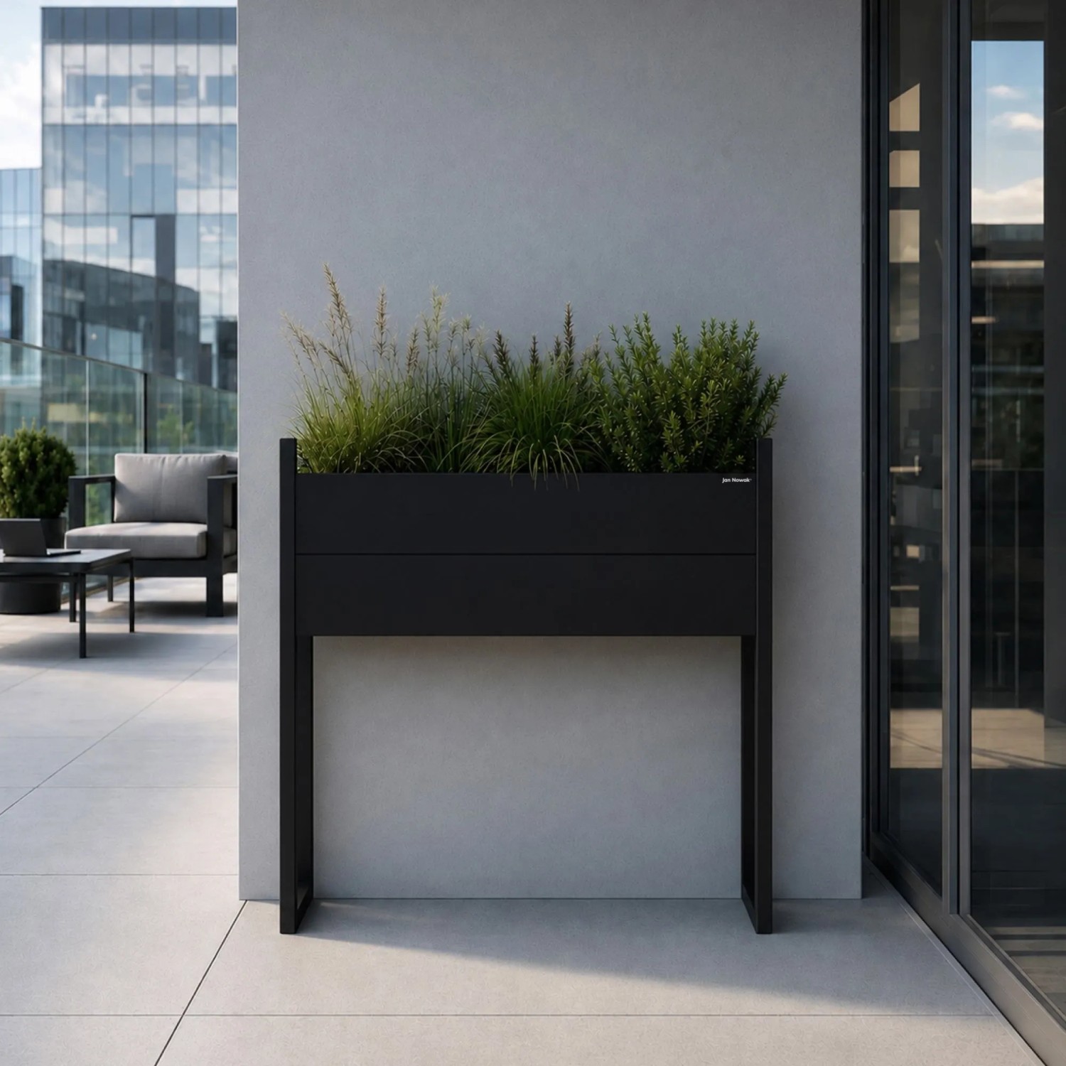 Hoher schwarzer Metall-Blumenkübel JAN NOWAK MARGARET H mit Pflanzen auf moderner Terrasse.