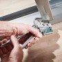 Hände verbinden Metallprofile mit wolfcraft Profil-Verbindungszange auf Holzboden. Crimpzange für Trockenbau.