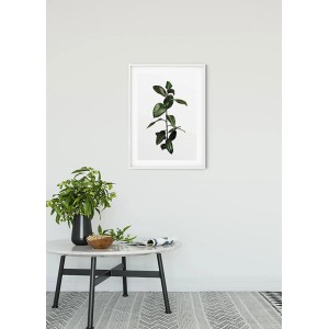 Wandbild Ficus Branch (50x70 cm) im weißen Rahmen über einem Tisch mit Dekoration.