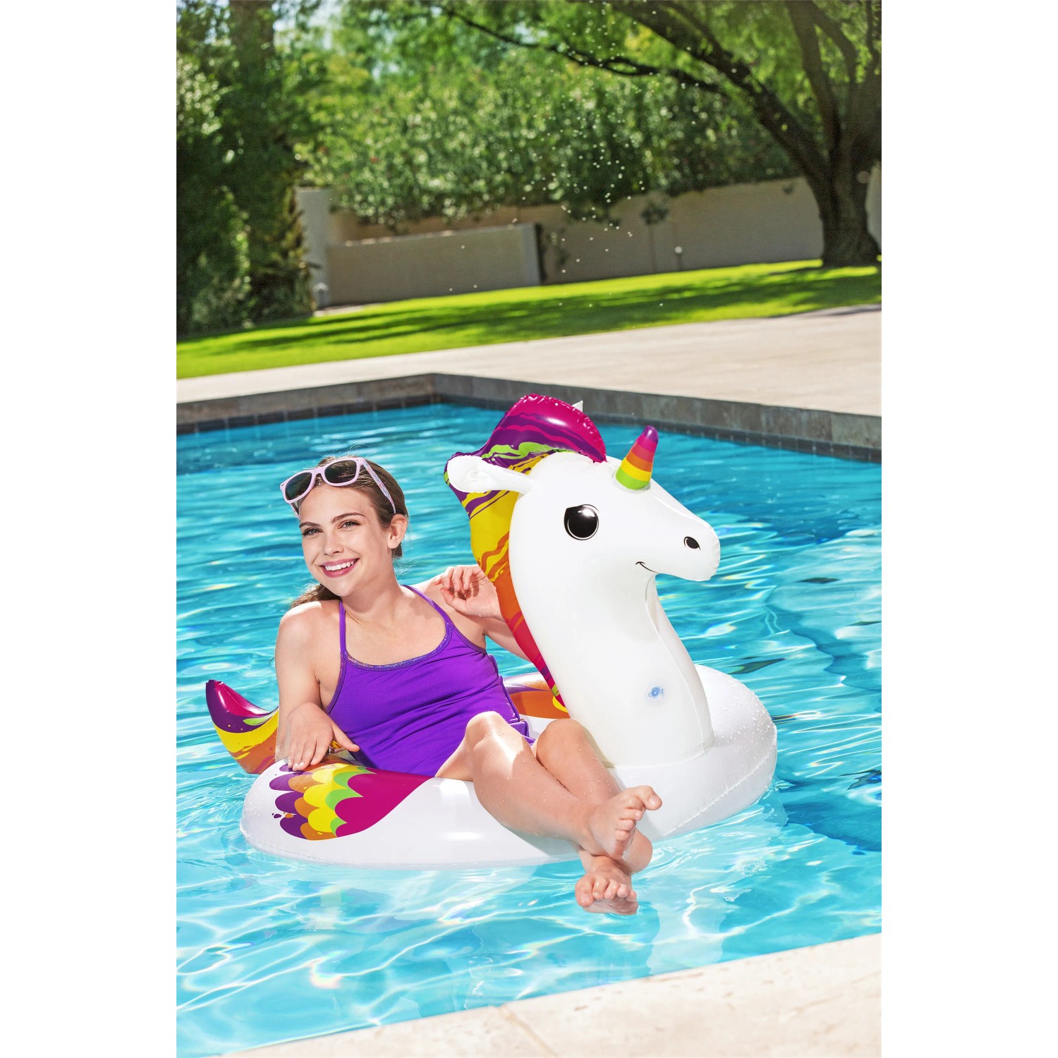 Frau auf Bestway Schwimmring Einhorn im Pool. Buntes Einhorn Design.