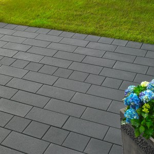 Verlegte Kann Vero Maxx Pflastersteine Graphit (40x20x7,5 cm) mit Blumenkübel und Rasen im Hintergrund.