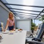 Anthrazit Terrassenüberdachung Bausatz 426x406 cm mit Polycarbonatplatten und sitzender Person am Tisch.