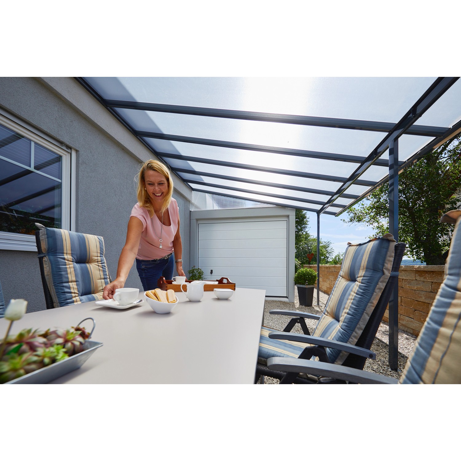 Anthrazit Terrassenüberdachung Bausatz 426x406 cm mit Polycarbonatplatten und sitzender Person am Tisch.