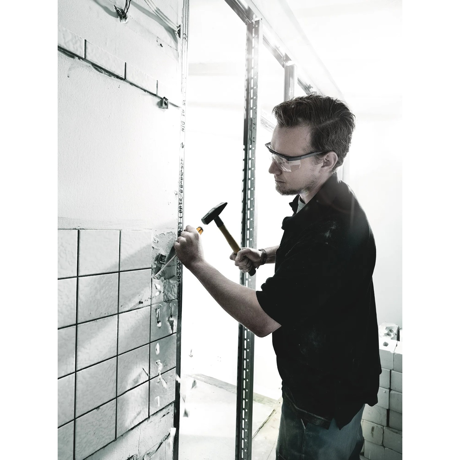 Handwerker stemmt Fliesen mit Wera Schraubendreher-Set und Hammer von der Wand.
