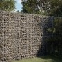 Große, befüllte Gabione mit Deckel aus Eisendraht als Sichtschutz im Garten.