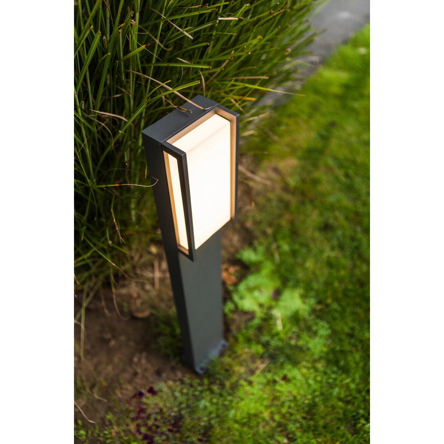 Moderne, anthrazitfarbene Lutec LED-Wegeleuchte Qubo mit warmweissem Licht im Garten.