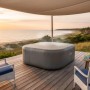 Graue, eckige Bestway LAY-Z-SPA EnergySense Thermo-Abdeckung auf einem Whirlpool auf Holzterrasse am Meer.