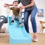 Glückliches Kind auf blauer KidKraft Rutsche des 5-in-1 Klettergerüsts, Erwachsener hilft. Vielseitiger Indoor/Outdoor Spielturm für Kinder.