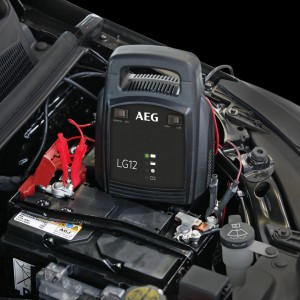AEG LG 12 Batterieladegerät im Einsatz zum Laden einer Autobatterie im Motorraum.