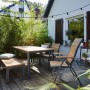 Gartenmöbel-Set mit Klappsessel Bonlee, Tisch, Bank und Stühlen auf einer Terrasse.
