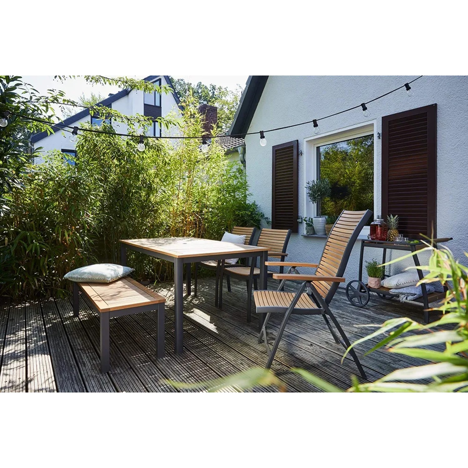 Gartenmöbel-Set mit Klappsessel Bonlee, Tisch, Bank und Stühlen auf einer Terrasse.