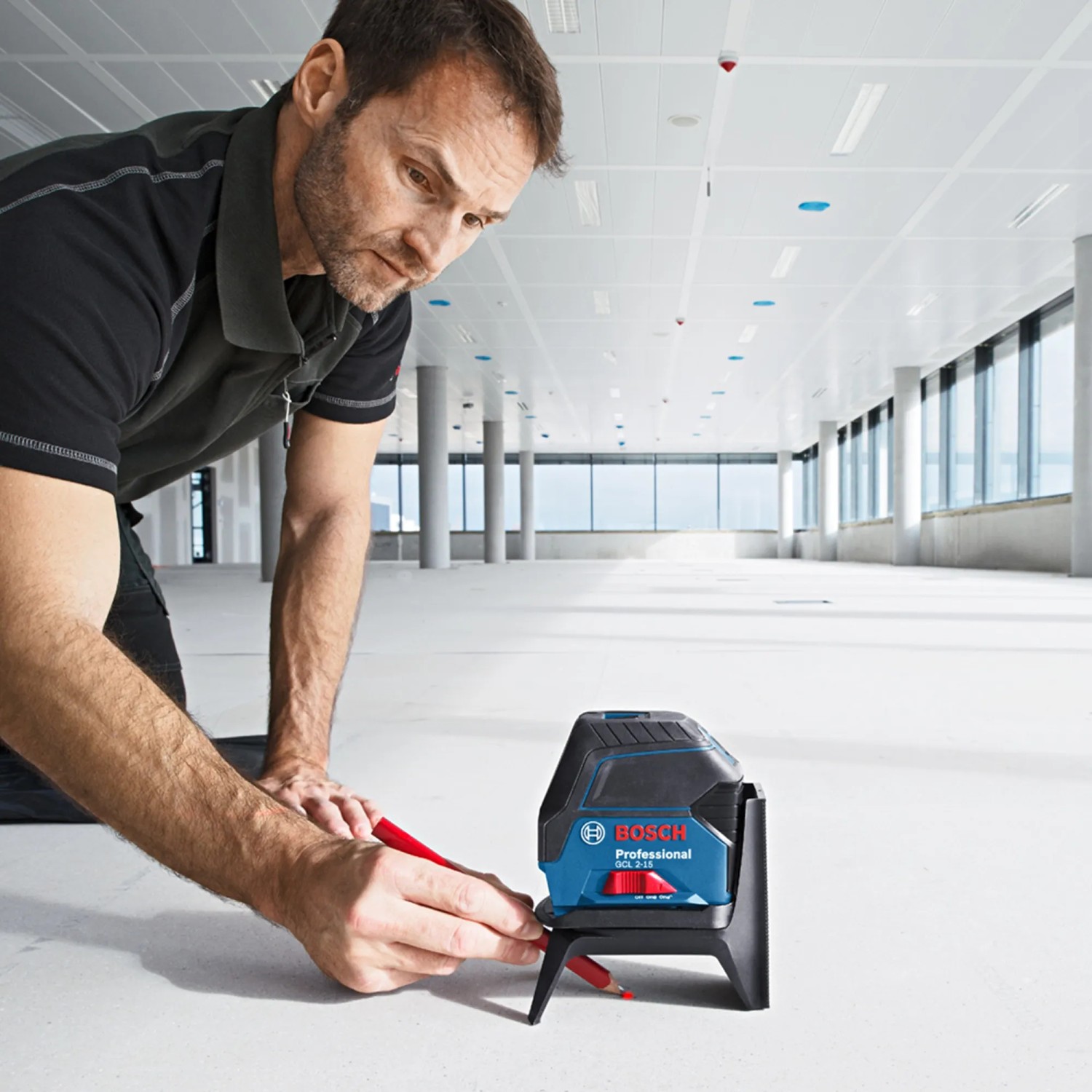 Handwerker justiert Bosch Professional Linienlaser GCL 2-15 auf Baustelle. Präzises Messwerkzeug für Profis.