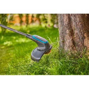 Gardena Akku-Rasentrimmer EasyTrim 25/18V Solo beim Trimmen von Gras an einem Baum.