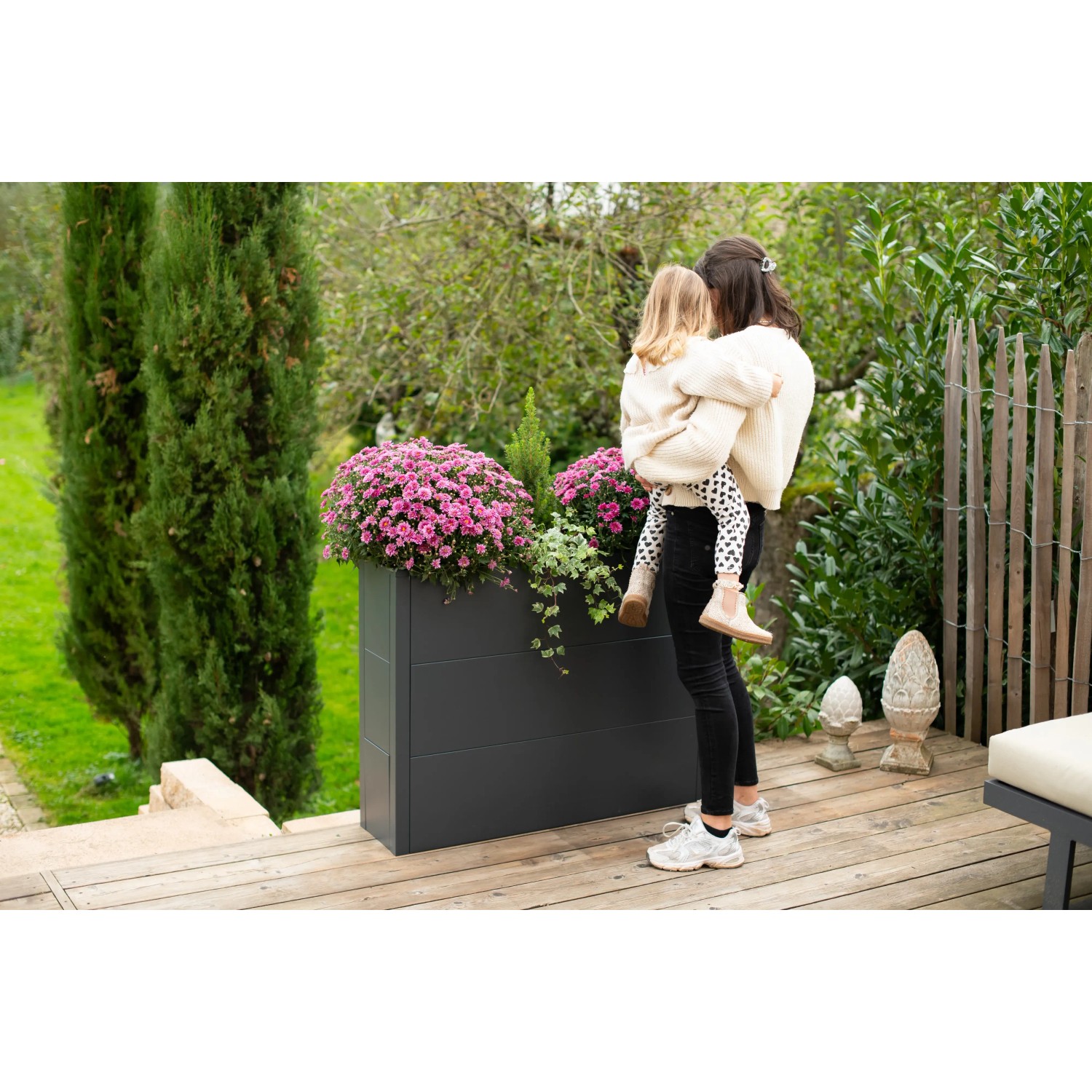 Westmann Pflanzkübel Talus XL, anthrazit, mit Blumen und Frau mit Kind im Garten.