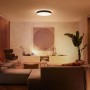 Schwarze Philips Hue Enrave XL Deckenleuchte mit warmweißem Licht im Wohnzimmer.