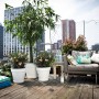 Weißer Elho Blumentopf Loft Urban (Ø 60 cm) mit Rollen auf einer Dachterrasse.