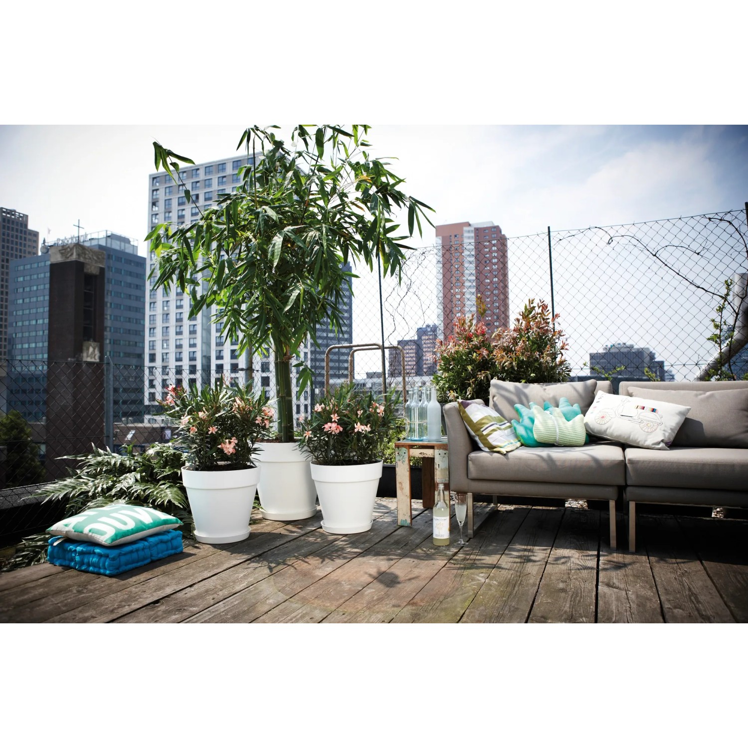 Weißer Elho Blumentopf Loft Urban (Ø 60 cm) mit Rollen auf einer Dachterrasse.