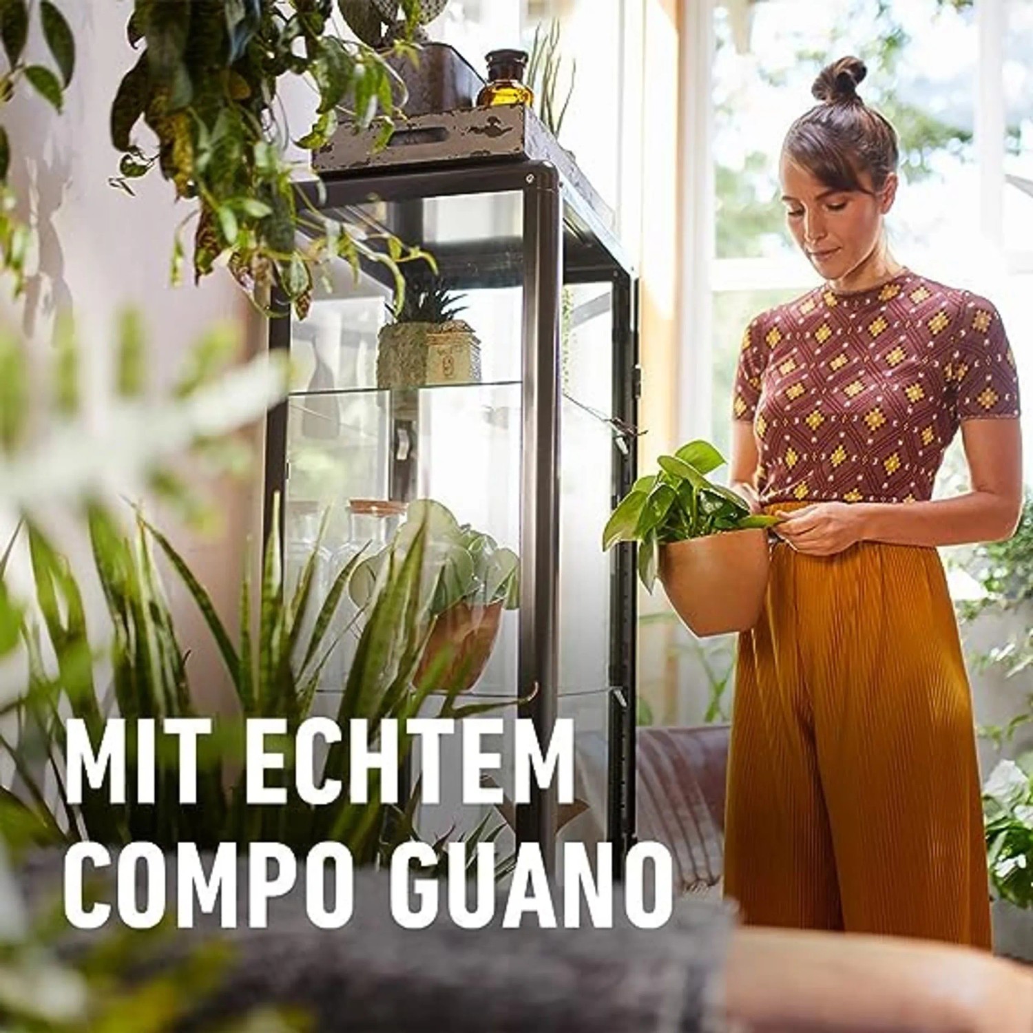 Frau mit Grünpflanze, im Vordergrund Werbung für Compo Düngestäbchen mit Guano.