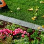 Grau-anthrazitfarbene Kann Rasenkante Nativa (35 cm) zwischen Rasen und Blumenbeet, mit Mähroboter.