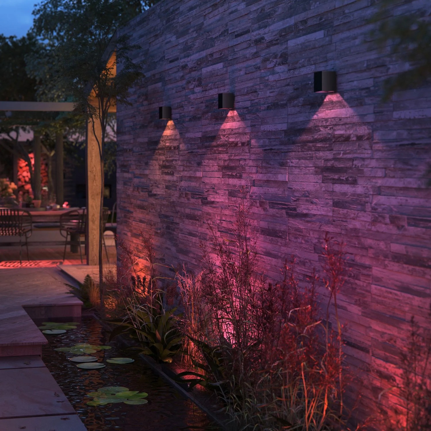 Philips Hue Resonate: Schwarze LED-Außenwandleuchten mit farbigem Lichtkegel an einer Steinwand.