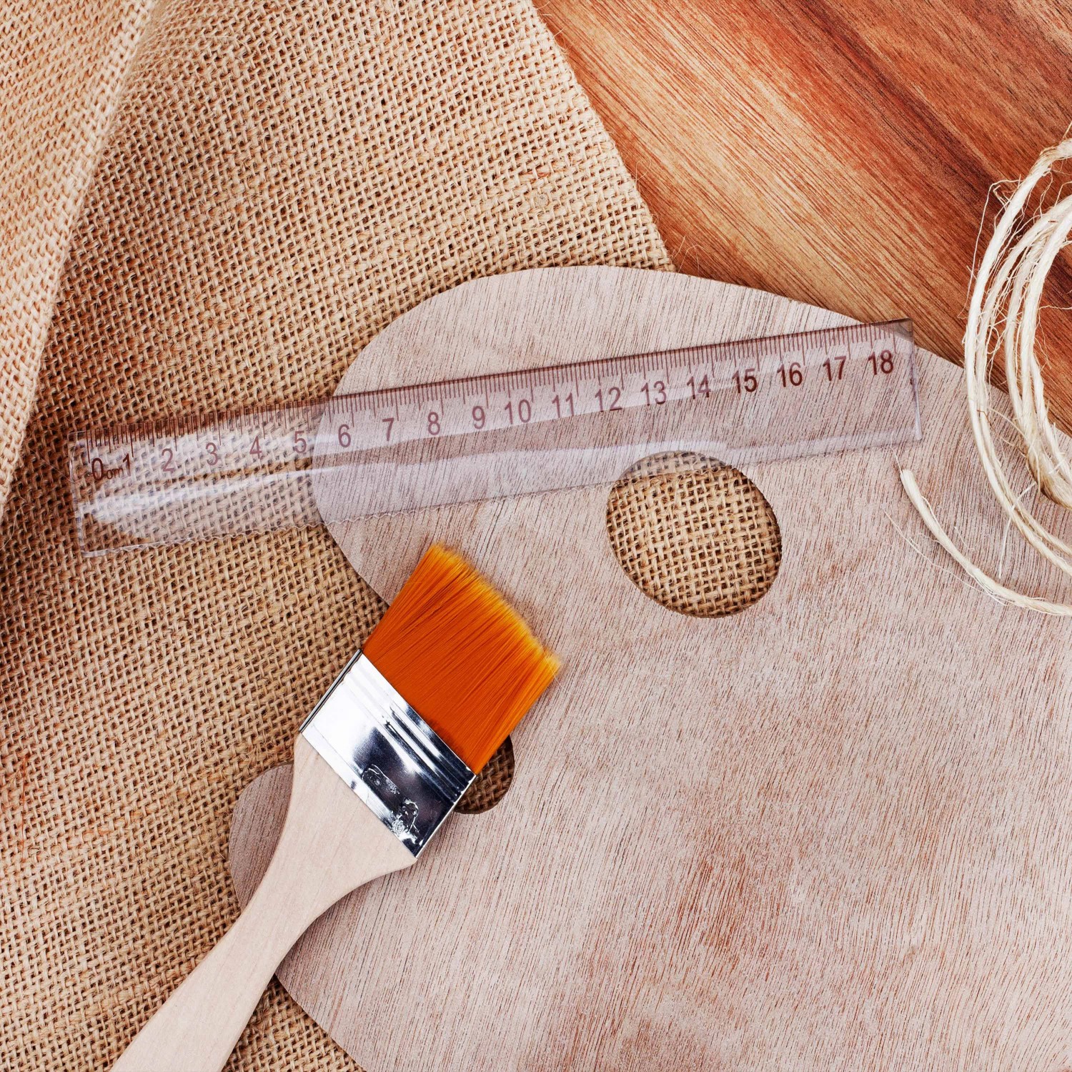 Jutegewebe mit Pinsel, Lineal und Palette auf Holz für Bastelarbeiten und Pflanzenschutz.