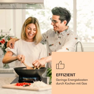 Lachendes Paar kocht mit Wok auf schwarzem Klarstein Goldflame Gaskochfeld aus Glaskeramik. Effizientes Kochen mit Gas.