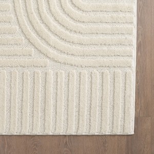 Cremefarbener Kurzflorteppich mit auffälligem 3D-Reliefmuster aus geschwungenen und geraden Linien auf Holzfußboden.