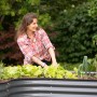 Frau gärtnert im anthrazitfarbenen Westmann Metall Hochbeet Grow Faster. Gemüse wächst.