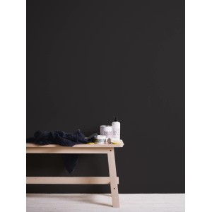 Schwarze Vliestapete Trendwall 2 Uni von A.S. Création an Wand hinter Holzhocker.