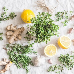 Glasbild Cook me: Stillleben mit Zitrone, Ingwer, Knoblauch und Kräutern auf Stoff.