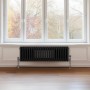 Schwarzer 3-Säulen Heizkörper (300x1012mm) vor Fenster. Traditioneller Stil für wohlige Wärme.